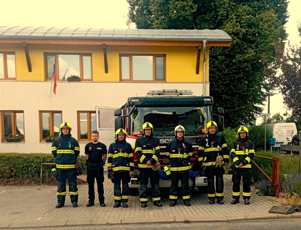 Členové Jednotky sboru dobrovolných hasičů města Chýně před hasičskou zbrojnicí s cisternou Scania